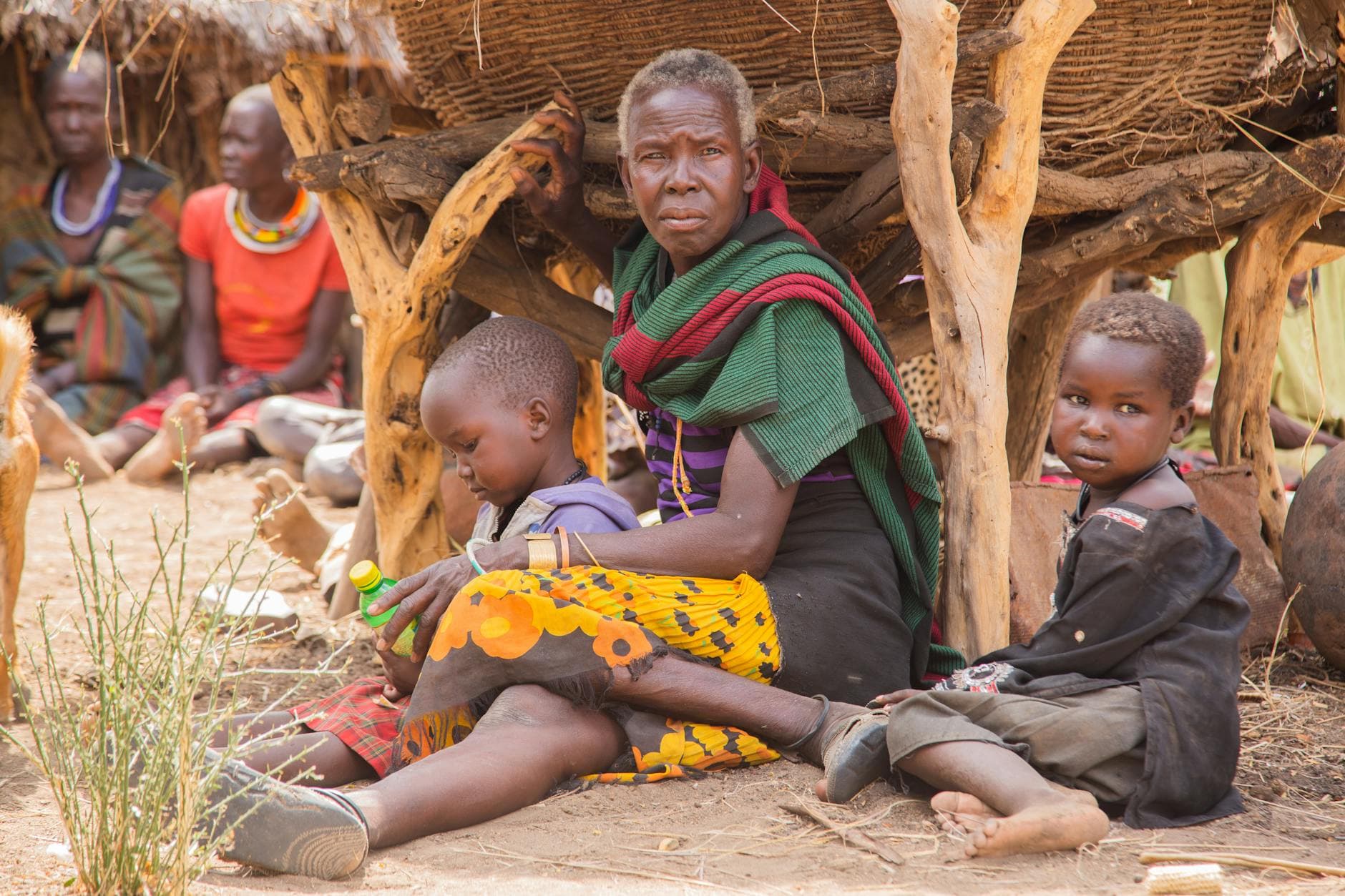 A family sits together in a traditional African village, embracing cultural heritage.