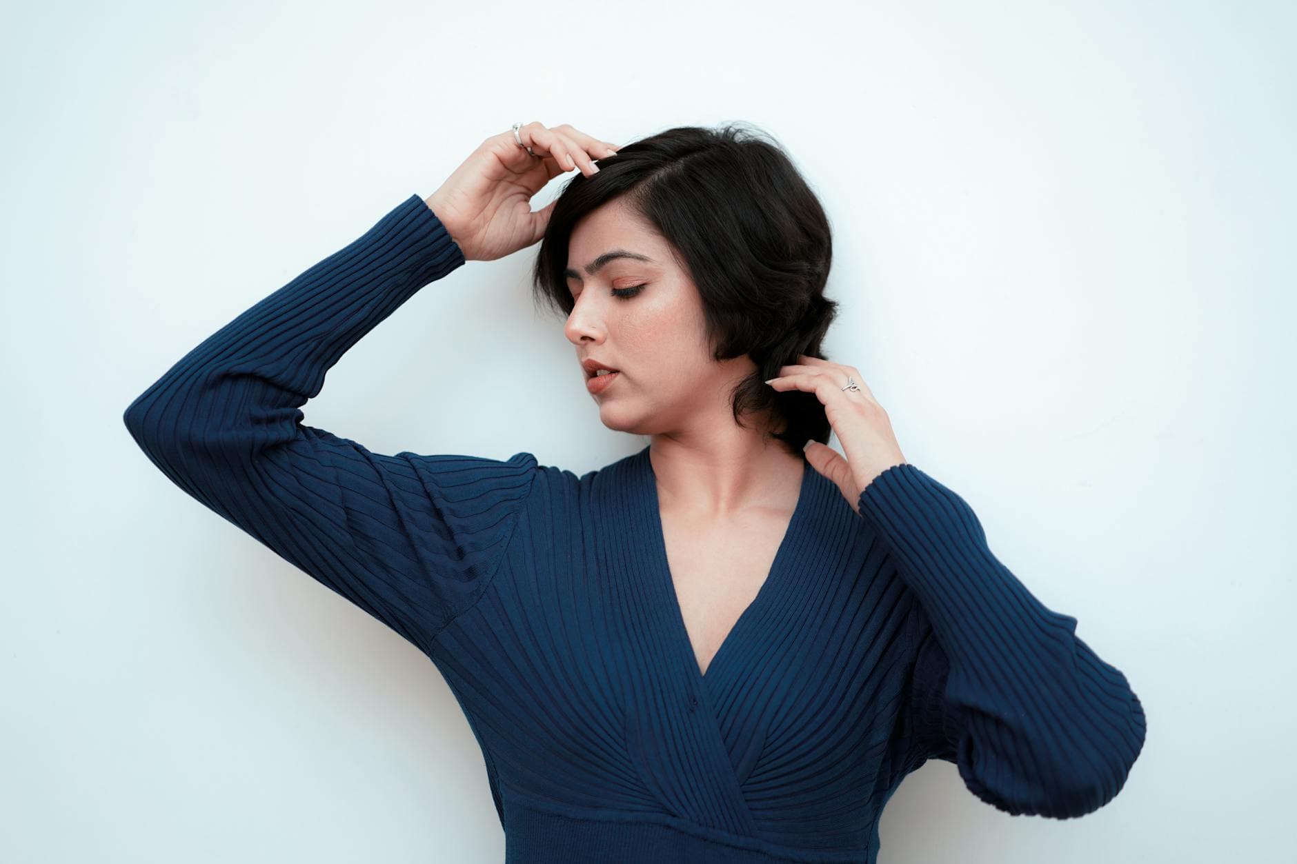 Serene portrait of a woman in a blue dress posing gracefully against white background.