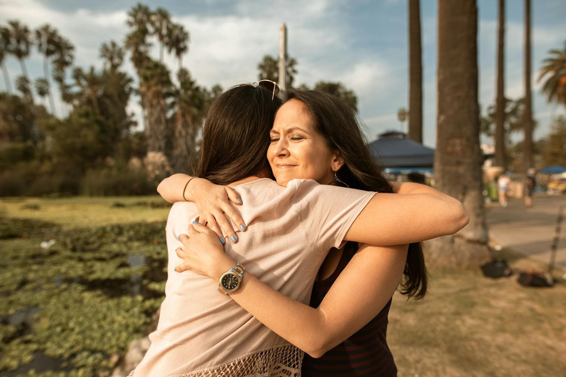 Two women hugging outdoors near a lake, conveying love and friendship.