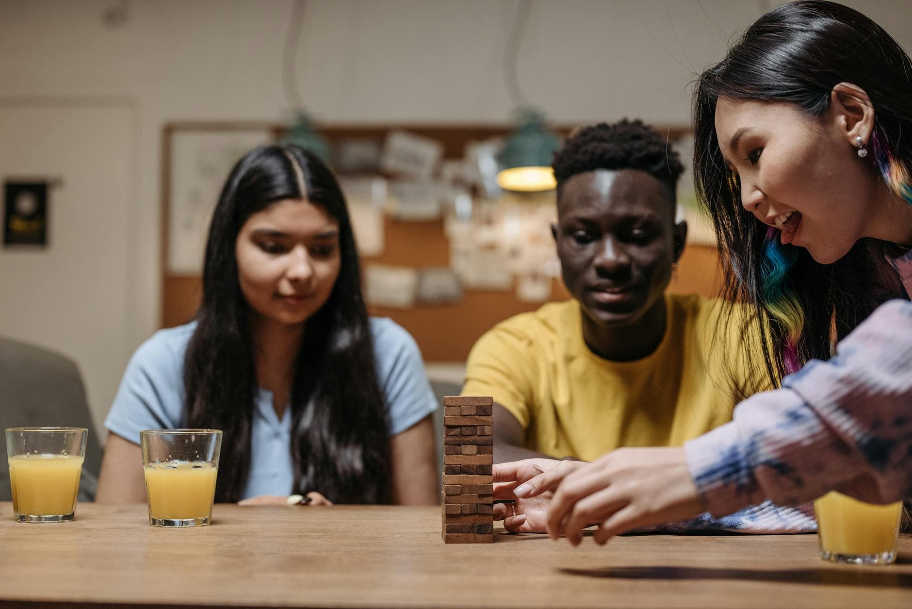 A diverse group of friends enjoying a game of Jenga indoors, fostering togetherness and fun.