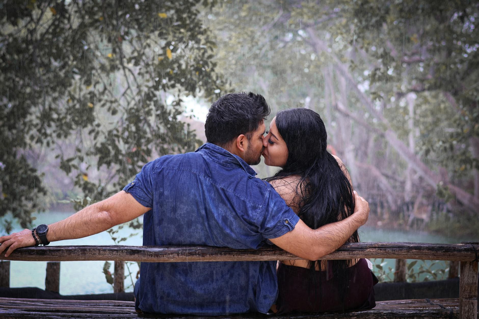 A couple embraces and kisses on a rainy day in Merida, Yucatan, Mexico, capturing a romantic moment outdoors.