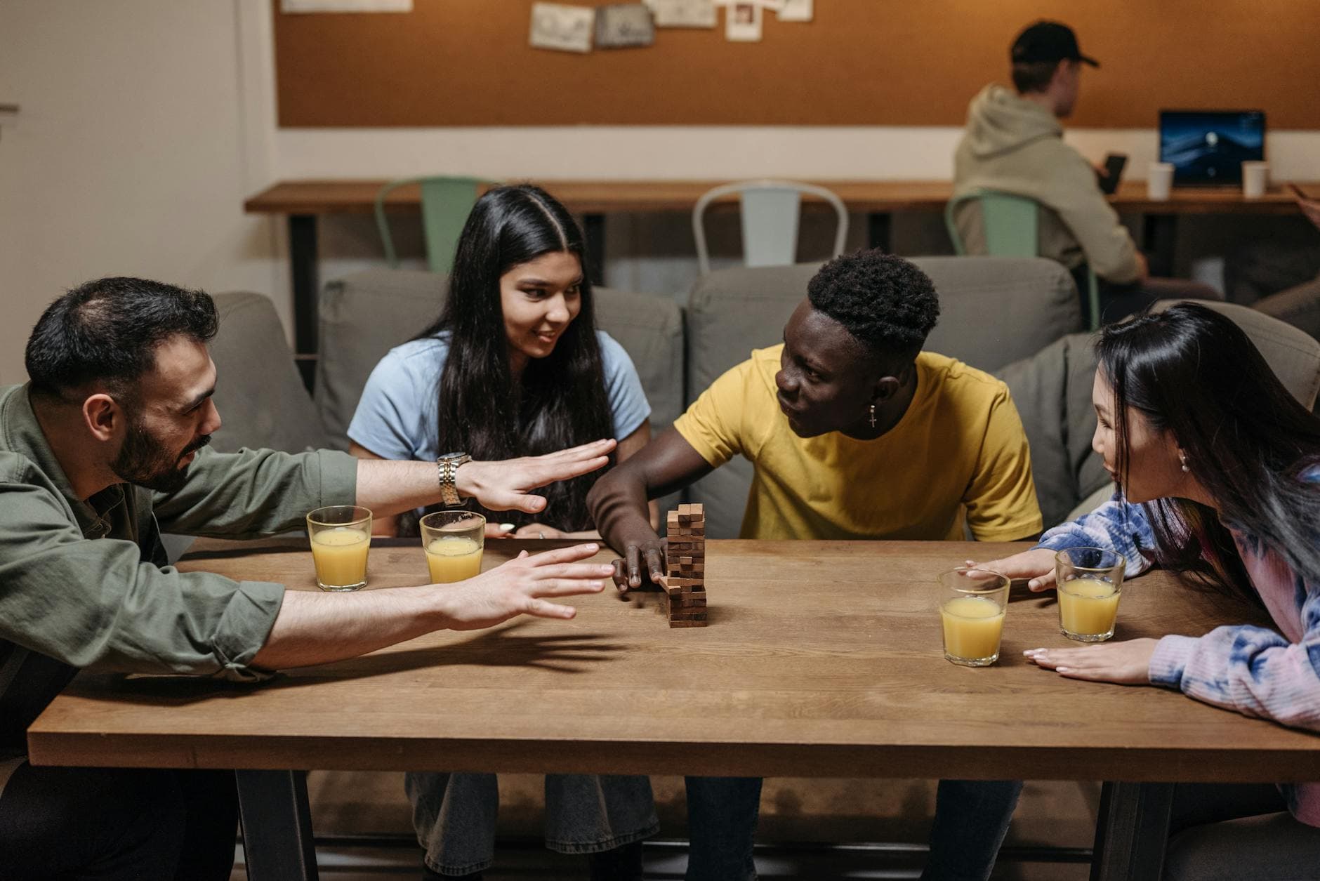 Friends engaging in a fun board game in a cozy indoor setting with drinks.
