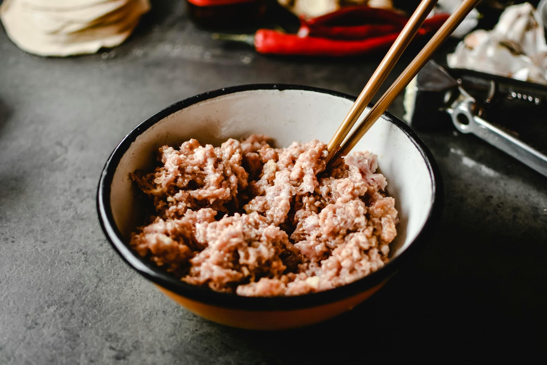 Close-up of raw ground pork in a bowl with chopsticks, ready for cooking.