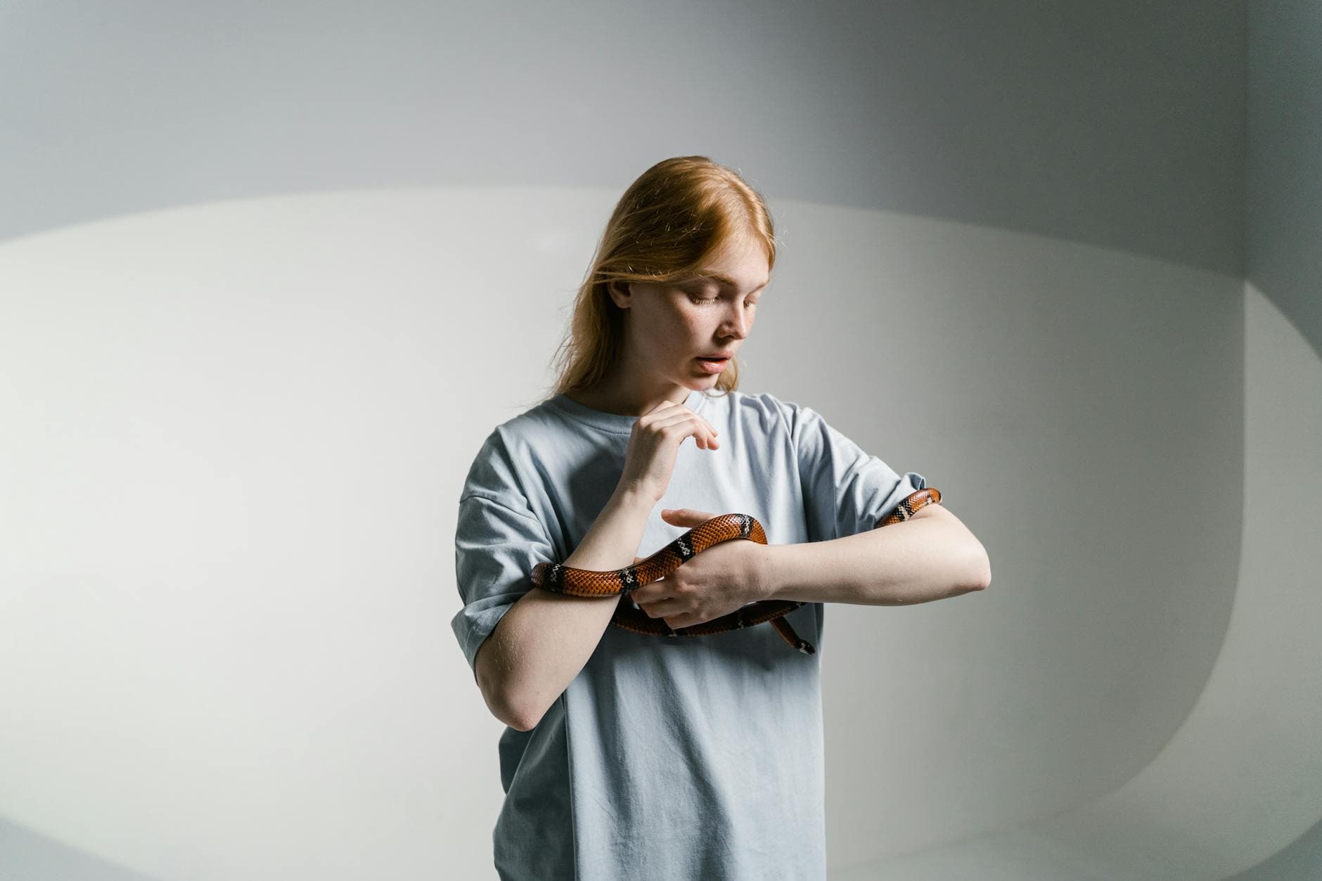 A woman calmly interacts with a snake in a well-lit indoor environment.