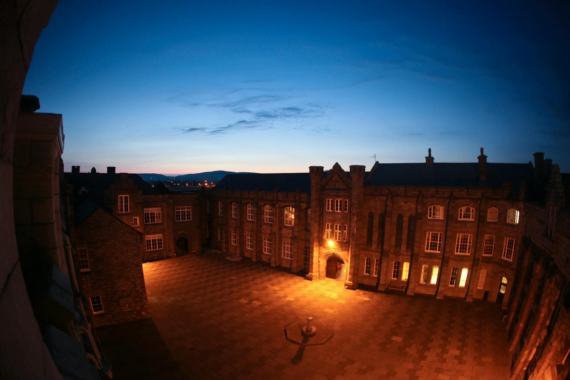 A historic college courtyard captured during twilight, showcasing architectural beauty and warm lighting.