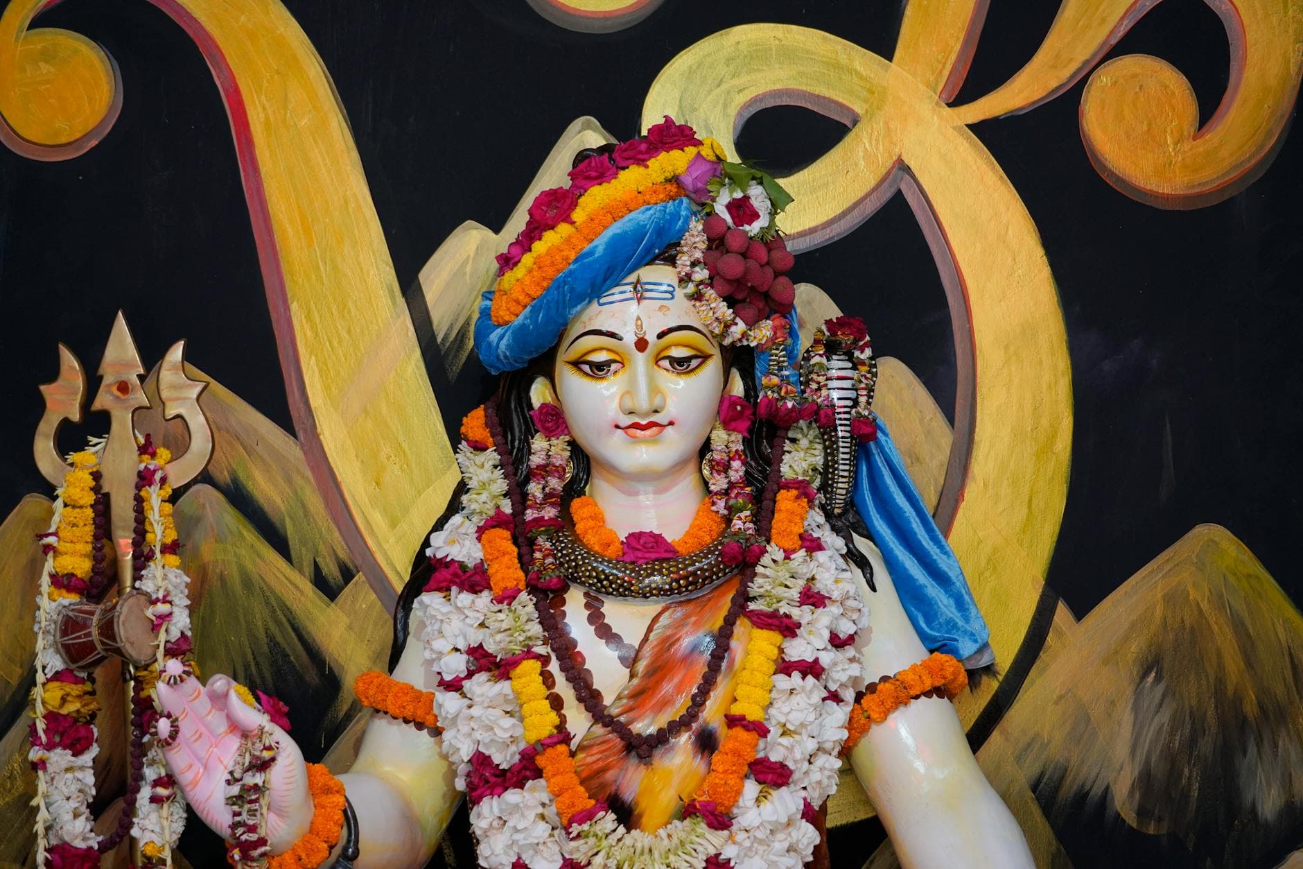 Colorful statue of Hindu god Shiva adorned with flowers, representing spiritual artistry and religious devotion.