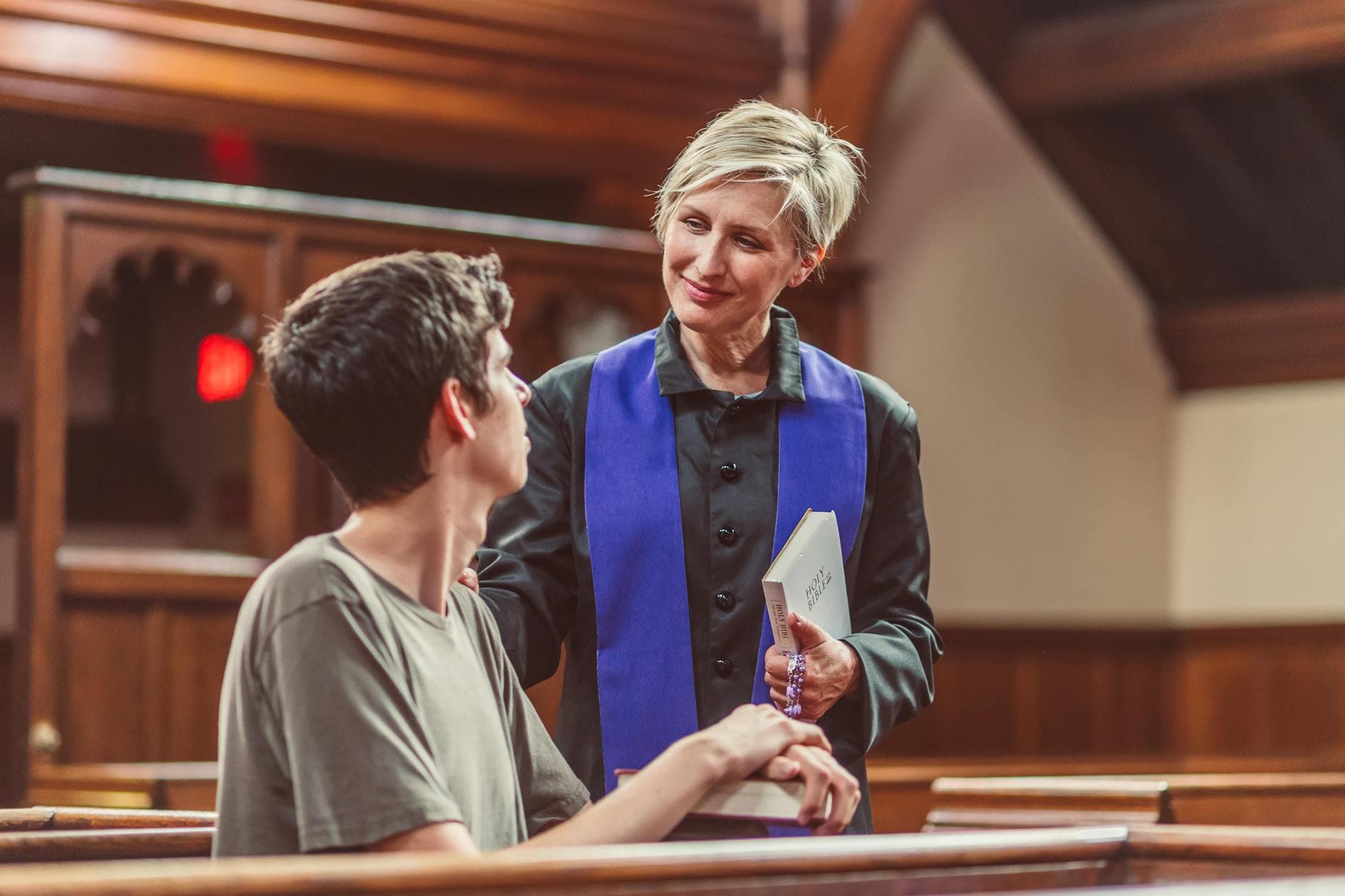 A clergy member and a young man in a warm conversation inside a church.