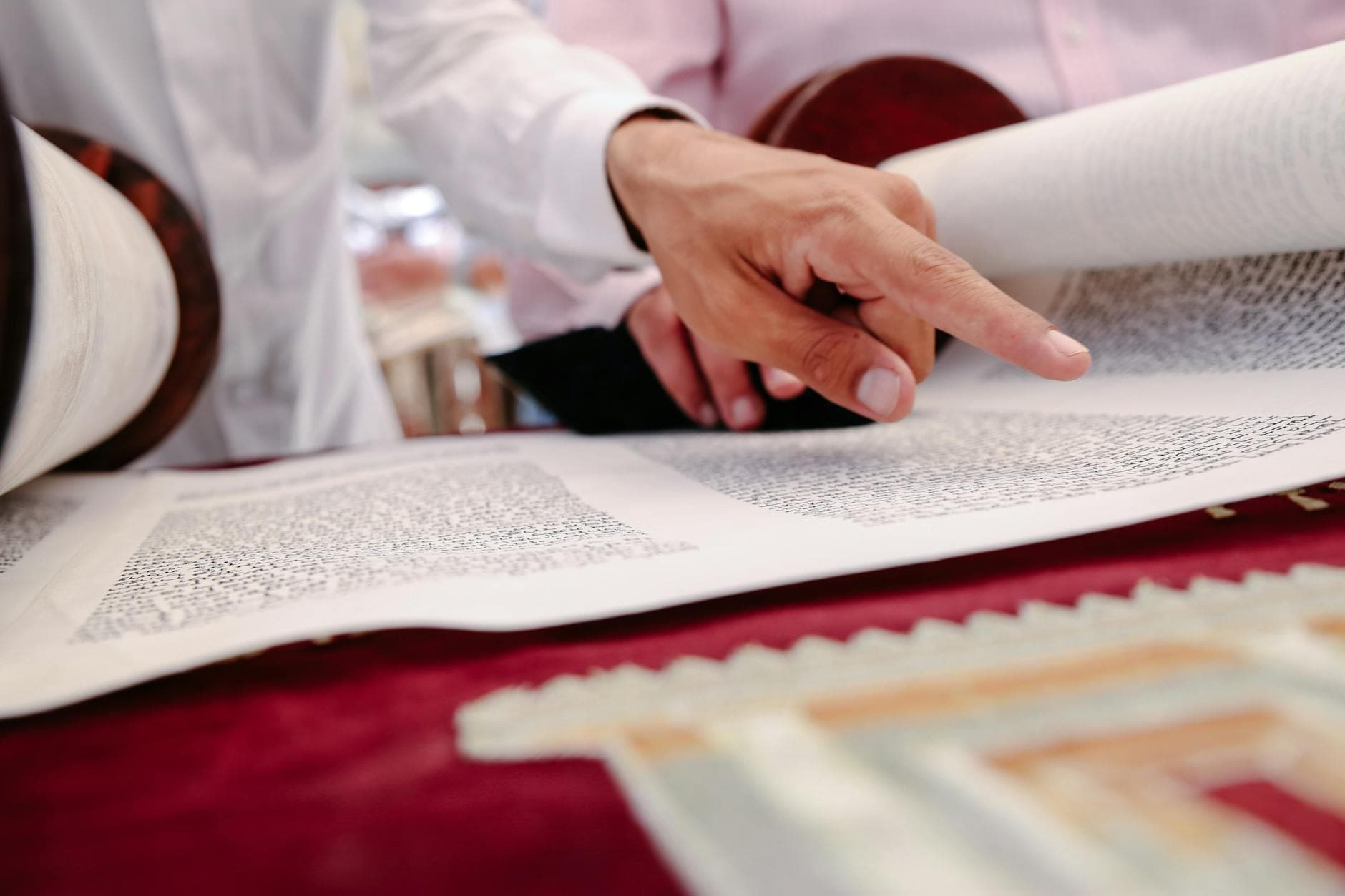 Hands pointing to text in a Torah scroll, symbolizing Jewish faith and traditions.