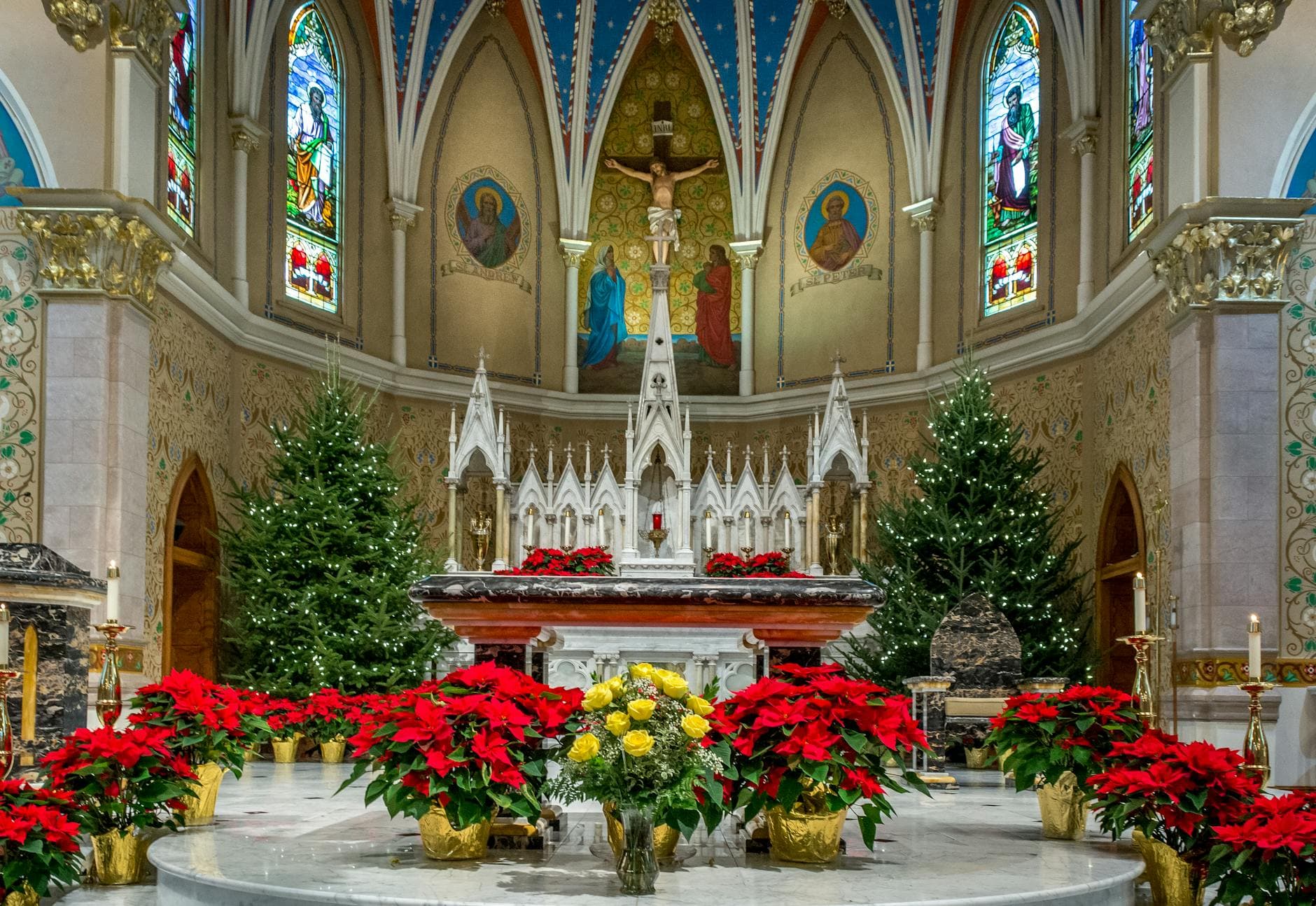 A beautifully decorated altar inside St. Andrew's Church with festive Christmas decorations and vibrant stained glass.