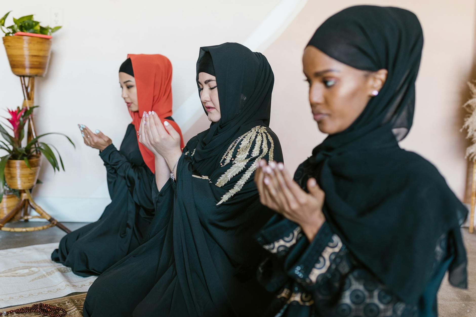 A serene scene of three women in hijabs praying indoors, reflecting Islamic faith and modest fashion.