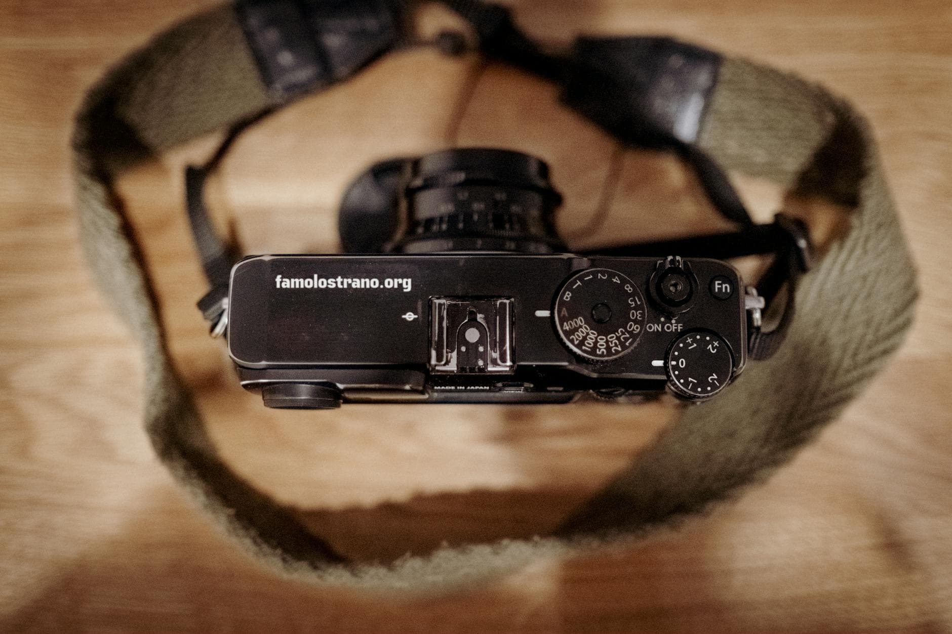 Close-up view of a retro black camera with strap on a wooden surface.