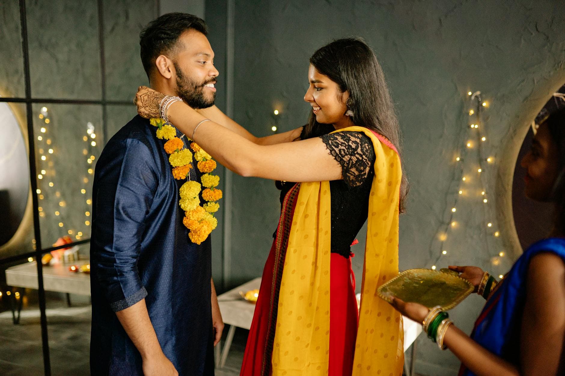 A joyful moment of a couple exchanging floral garlands during a traditional Indian celebration indoors.