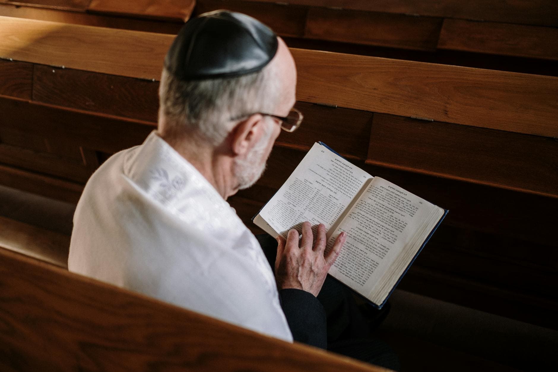 A senior man reads the Torah inside a synagogue, highlighting Jewish culture and tradition.