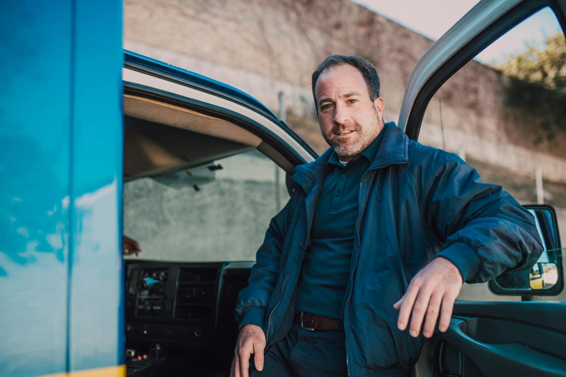 A smiling paramedic standing by the open door of an ambulance, ready for action.
