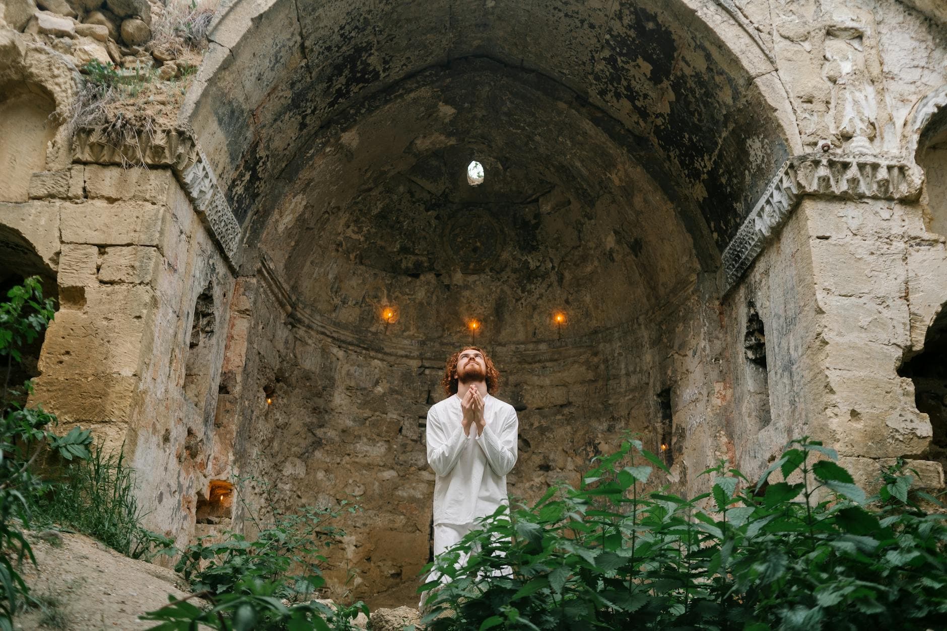 A man in prayer inside an ancient stone chapel, exuding spiritual devotion and solemnity.