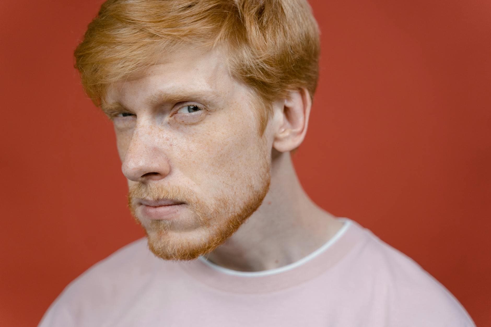 Portrait of a skeptical man with red hair and freckles, showcasing a doubtful expression.