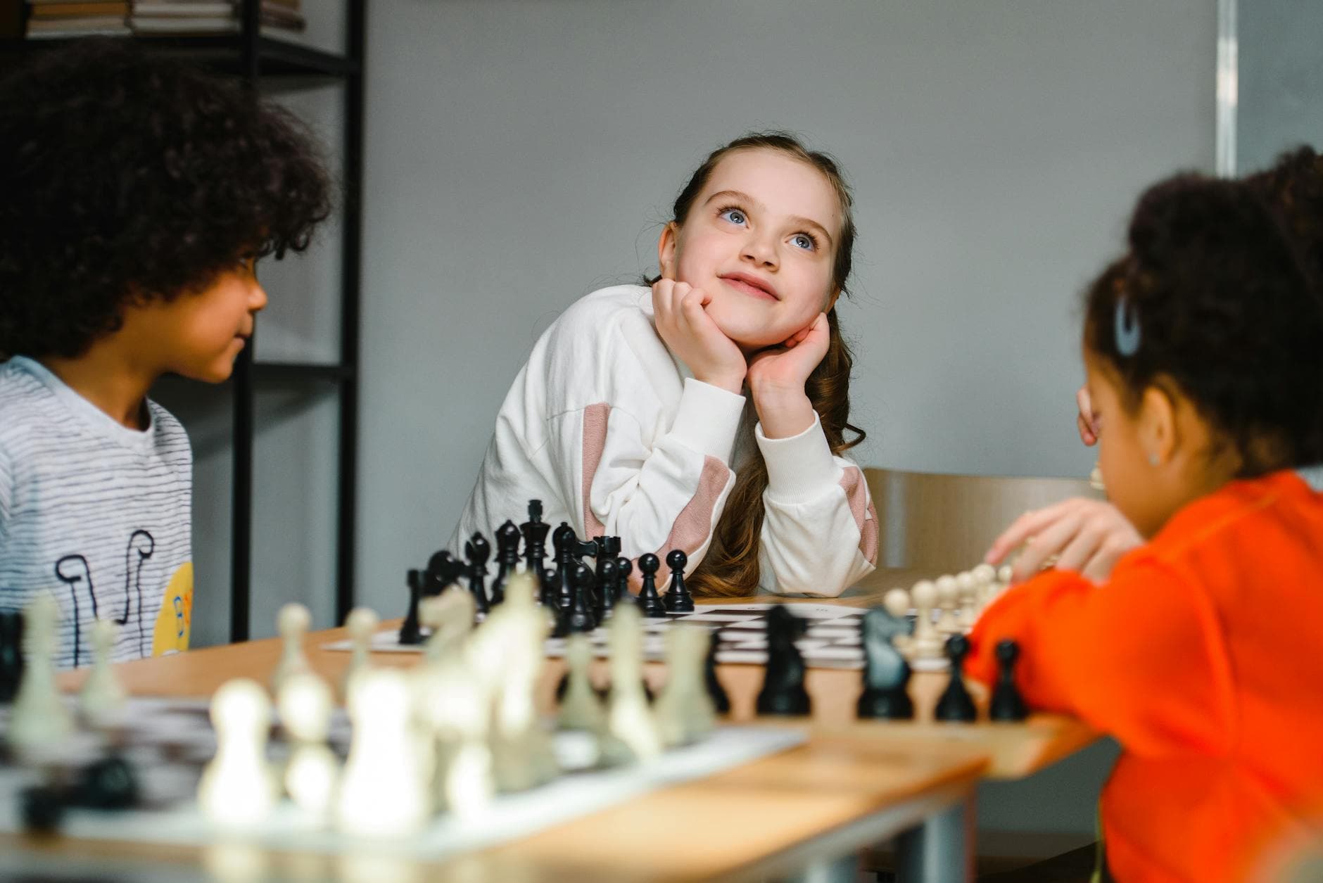Kids playing chess indoors, focusing on strategy and creativity, showcasing diversity and playful learning.