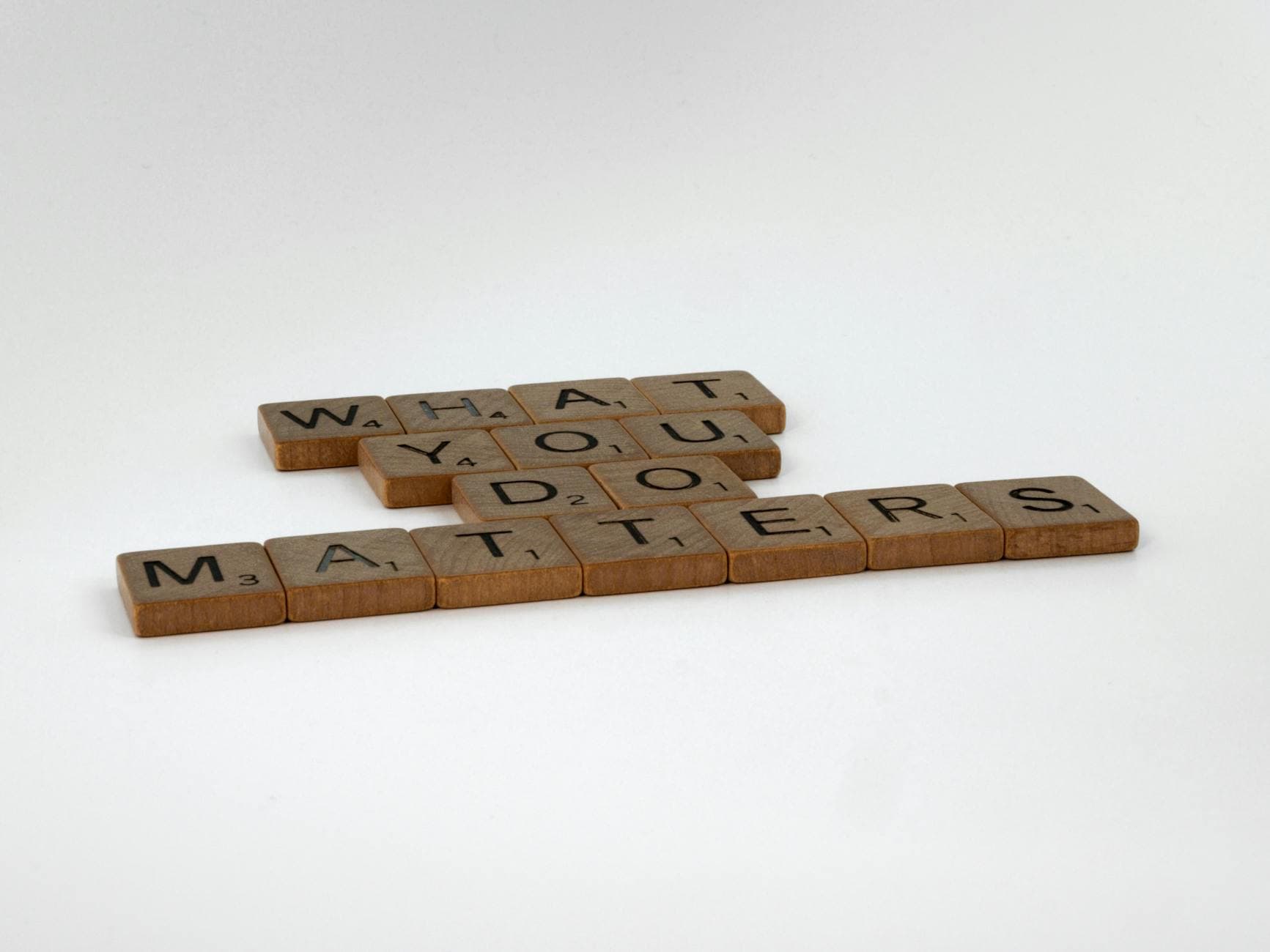 Scrabble tiles form the motivational phrase 'What You Do Matters' on a white background.